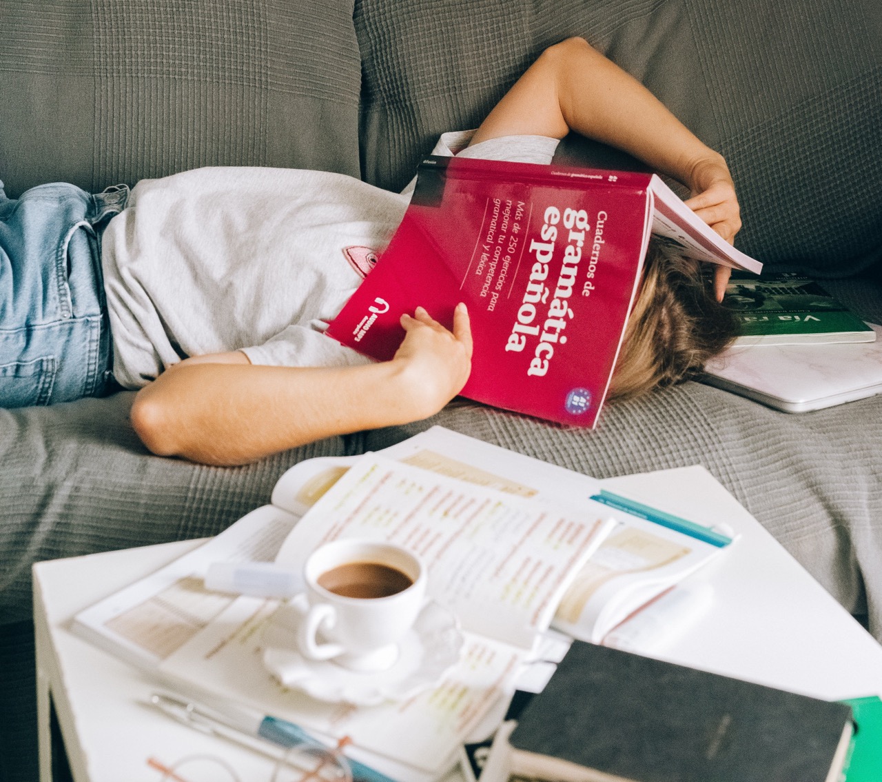 Übersetzungsbüro ALLESPRACHEN - Muttersprachenprinzip - Person müht sich mit Spanischbuch ab und hat das aufgeschlagene Grammatik-Buch über dem Gesicht